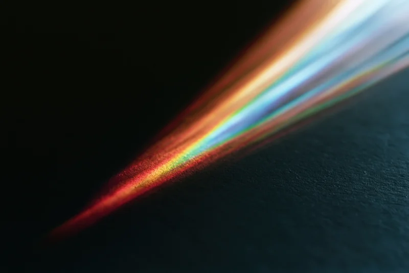 Prismatic light refraction casting a spectrum arc across a dark surface