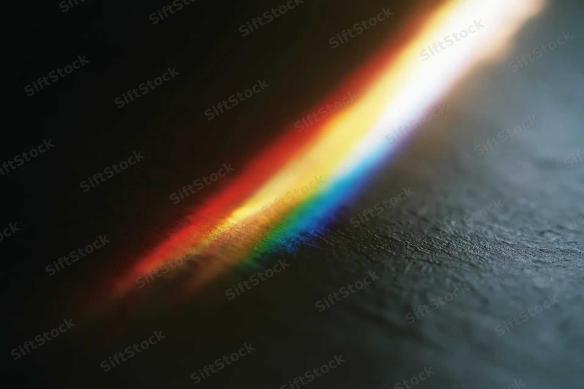 Prismatic light spectrum refracting across a dark textured surface