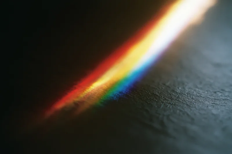 Prismatic light spectrum refracting across a dark textured surface