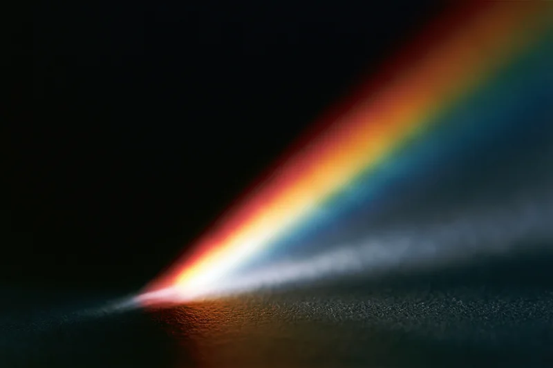 Prismatic light refraction spreading across a dark surface