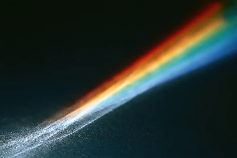 Prismatic light spectrum refracting across a dark surface