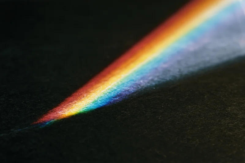 Prismatic light spectrum spreading across a dark textured surface