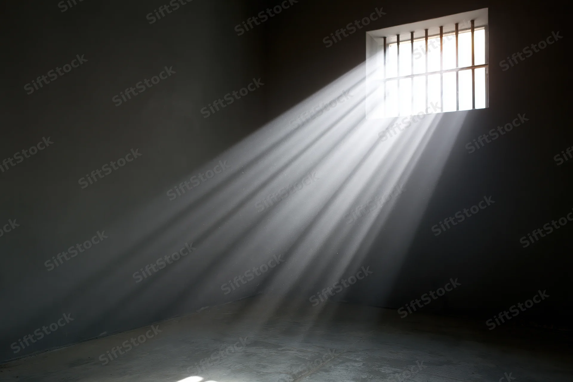 Rays of daylight streaming through a barred window in a prison cell interior