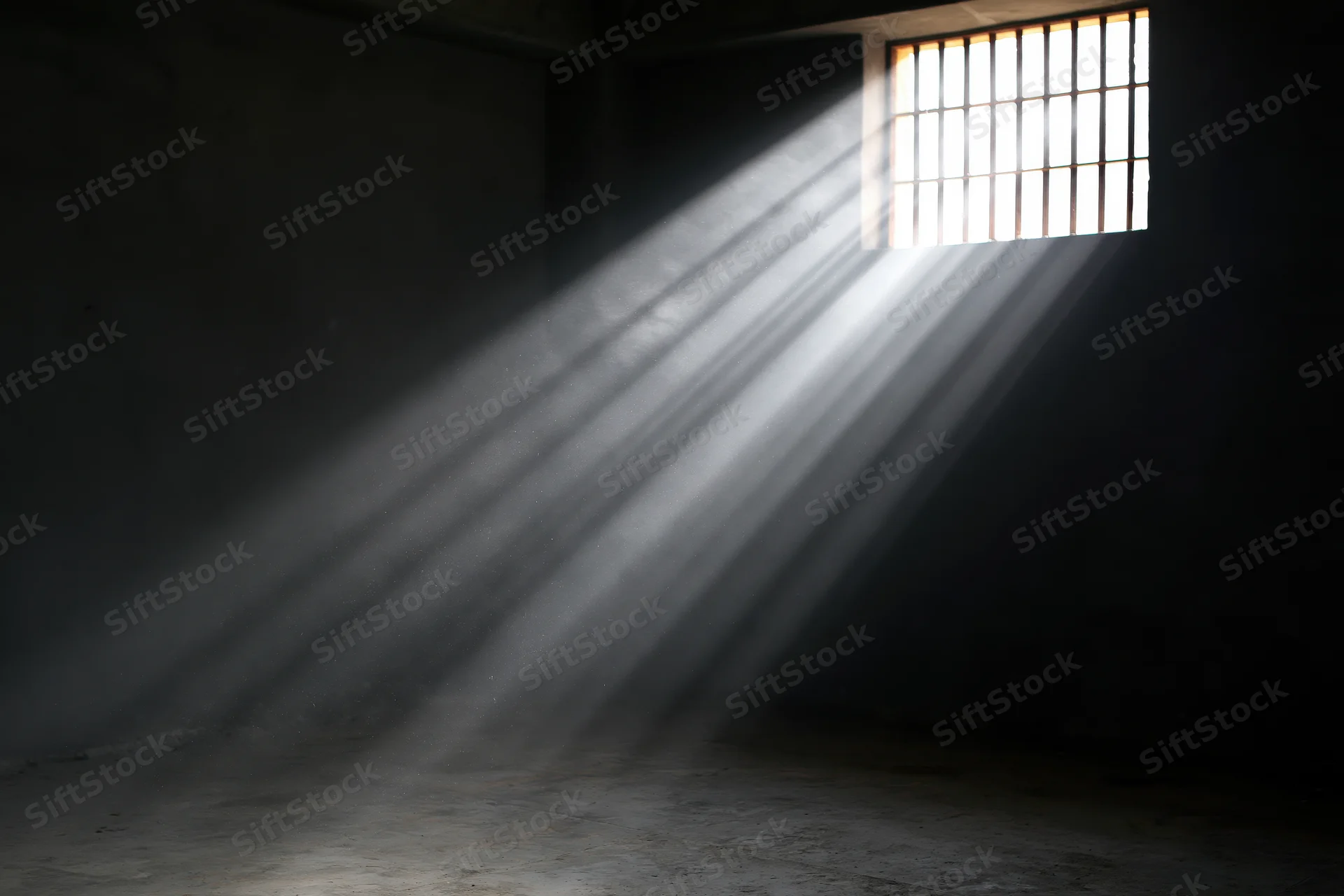 Sunlight streaming through barred window in prison cell interior
