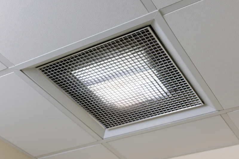 Recessed fluorescent ceiling light fixture in an office grid ceiling