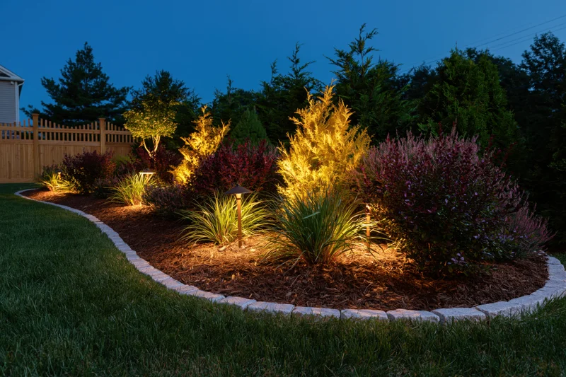 Residential garden bed illuminated by low-voltage uplights at dusk