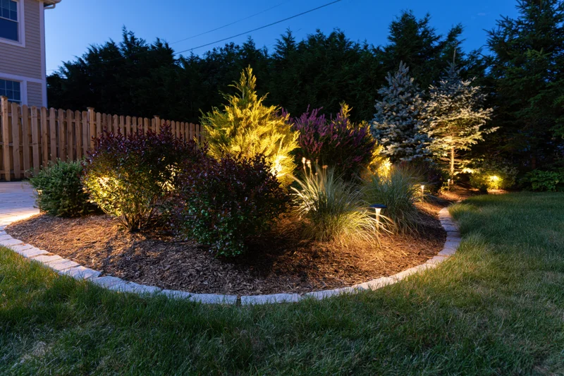 Residential garden bed illuminated by low-voltage uplights at dusk