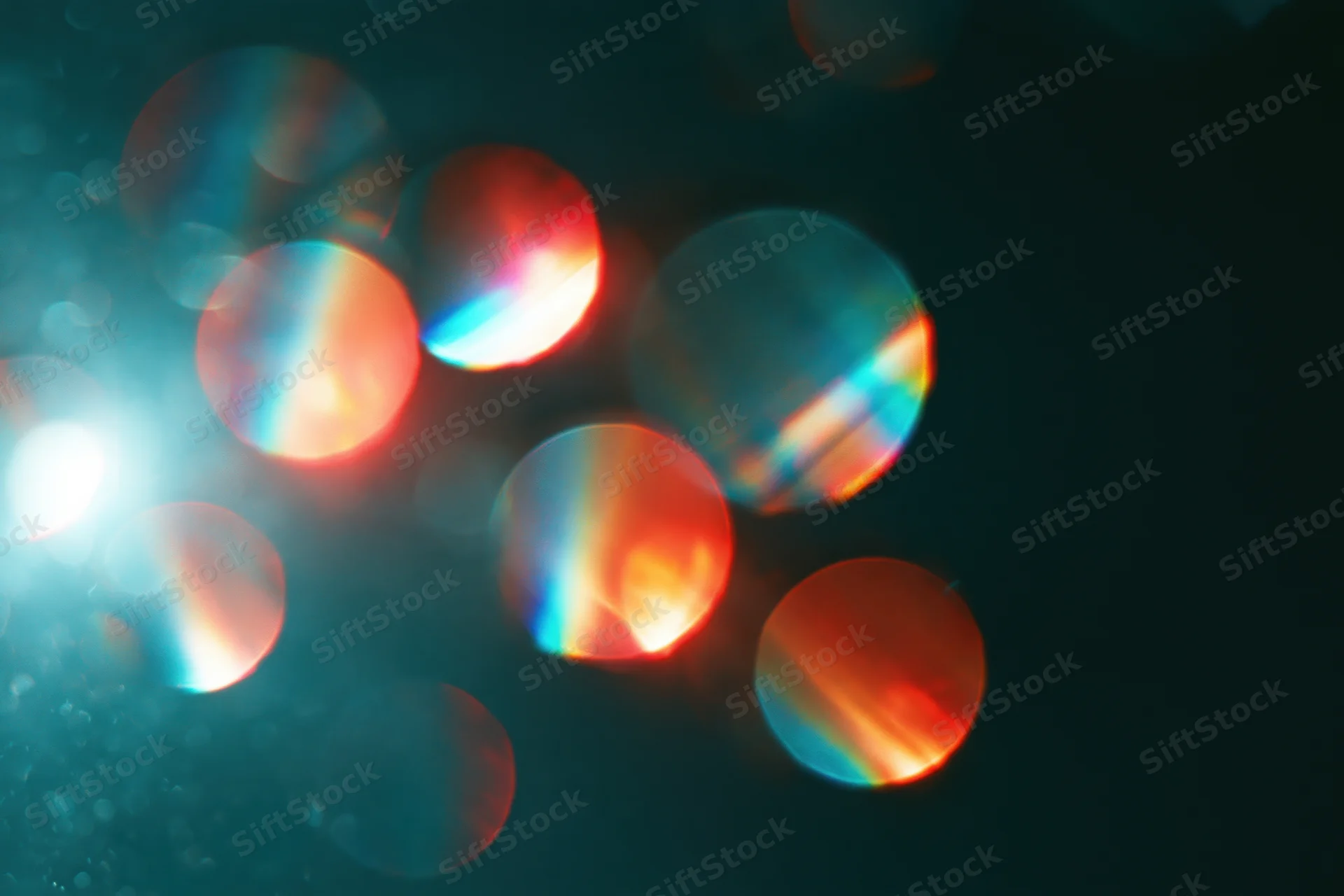 Scattered rainbow light refractions floating against a deep dark background