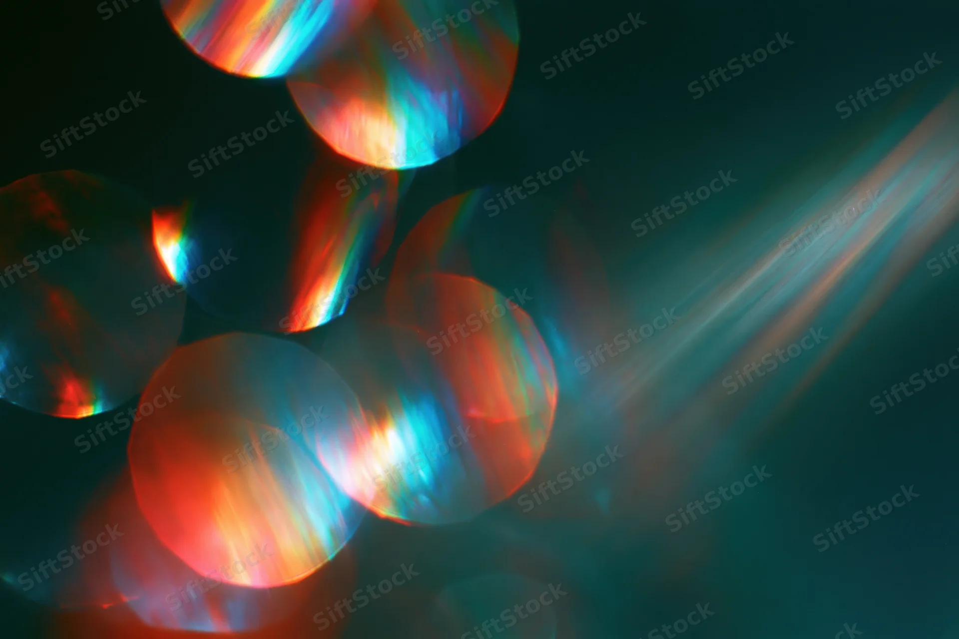 Scattered rainbow light refractions floating against a deep dark background
