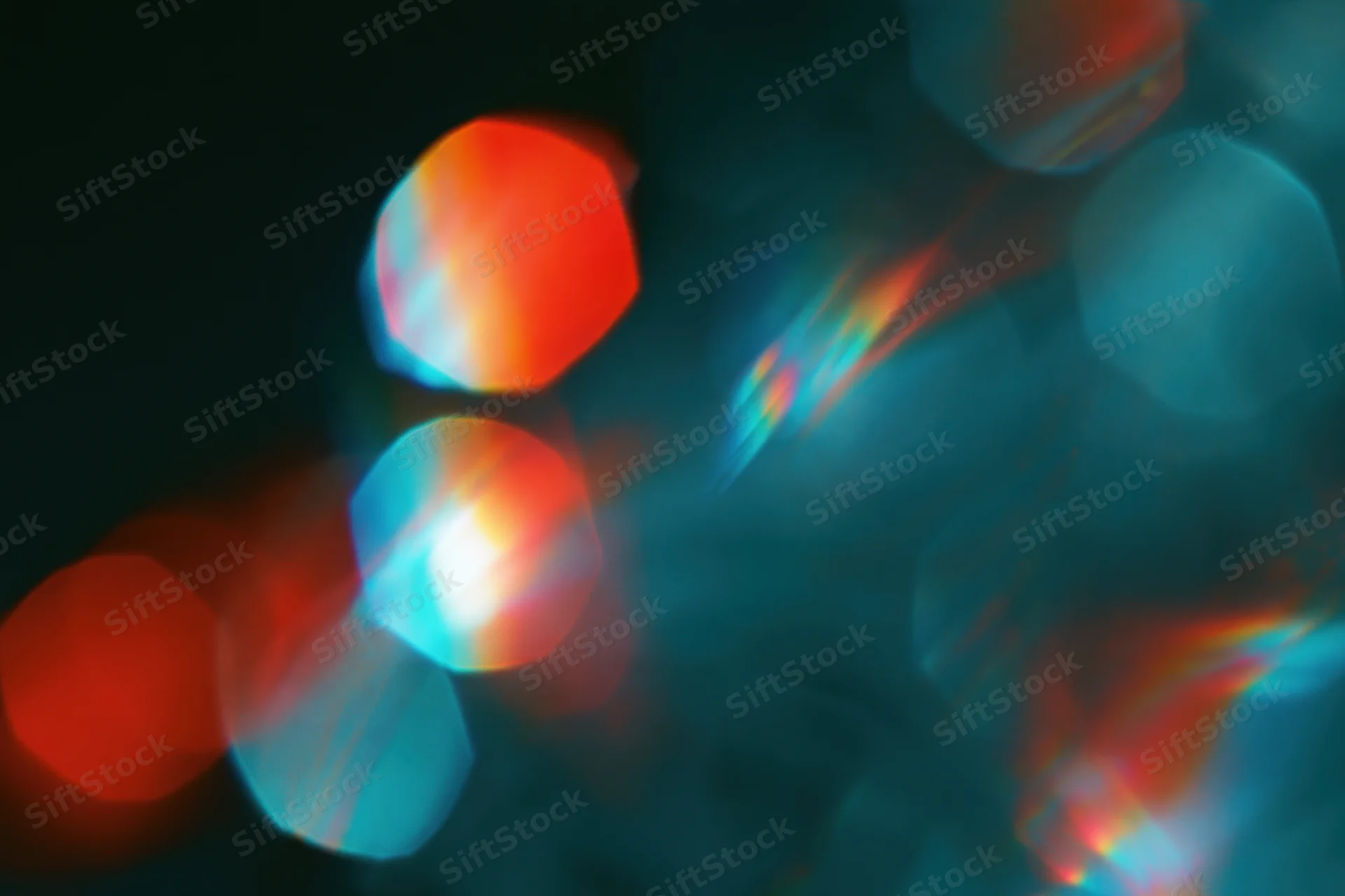 Scattered rainbow light refractions floating against a deep dark background