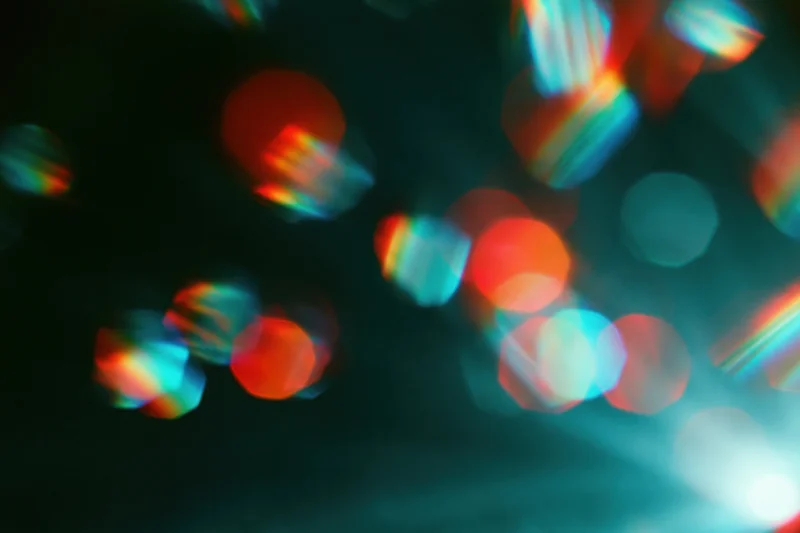 Scattered rainbow light refractions floating against a dark background