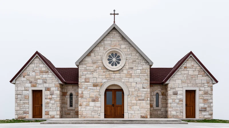 Small limestone community church with central peaked gable and cross on roof, symmetrical facade featuring arched wooden doors and rose window, set on stone platform against plain sky
