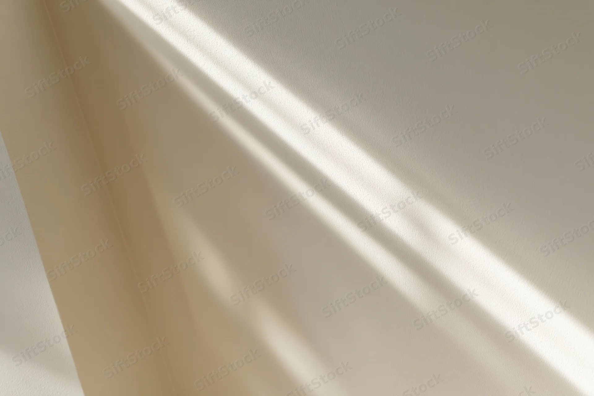 Diagonal window light casting soft shadows across an off-white interior wall corner