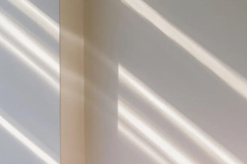 Diagonal window light shadows falling across plain off-white interior walls