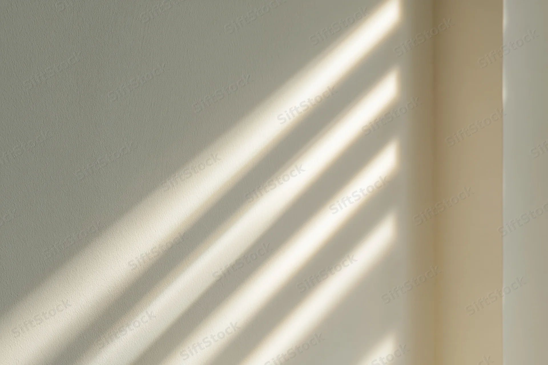 Diagonal sunlight shadows cast across a plain off-white interior wall corner