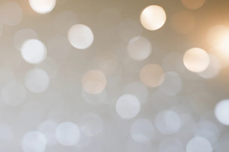 Soft out of focus bokeh lights scattered across a warm white background with circular glows and subtle gradient