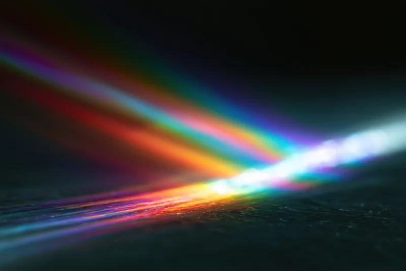 Prismatic light diffraction spreading across a dark textured surface