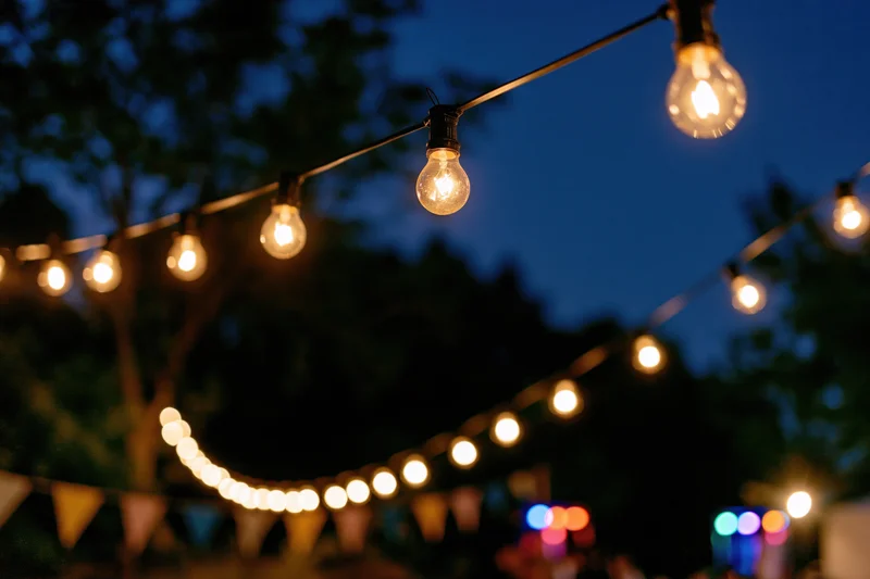 Strings of warm edison bulbs hanging outdoors at evening twilight