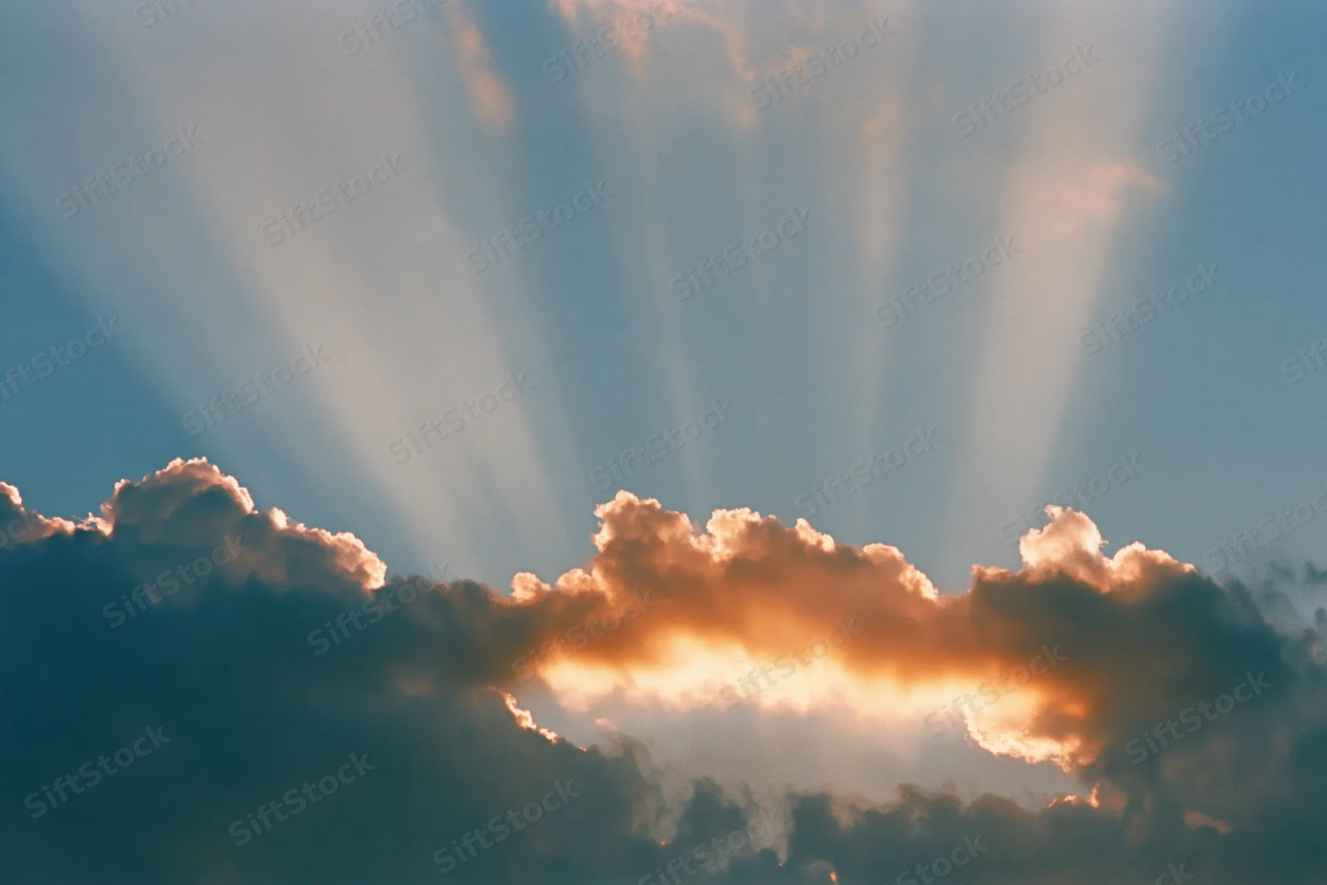 Sun rays breaking through dense cloud bank in sky
