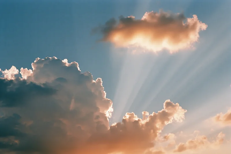Sun rays breaking through dense clouds in a blue sky