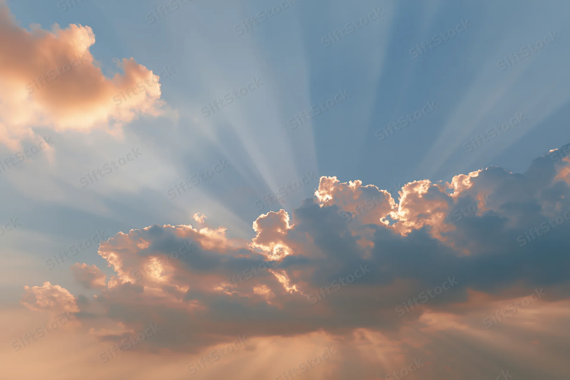 Sun rays breaking through layered clouds in open sky