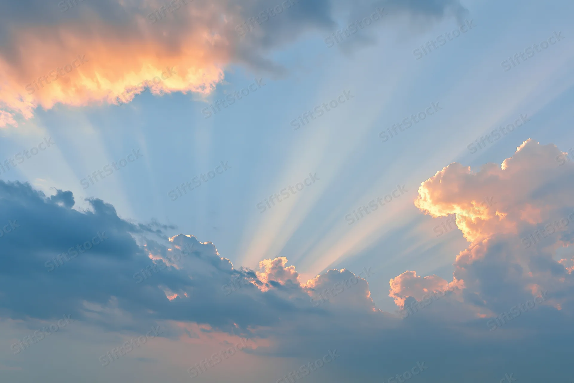 Sun rays breaking through layered clouds in an open sky