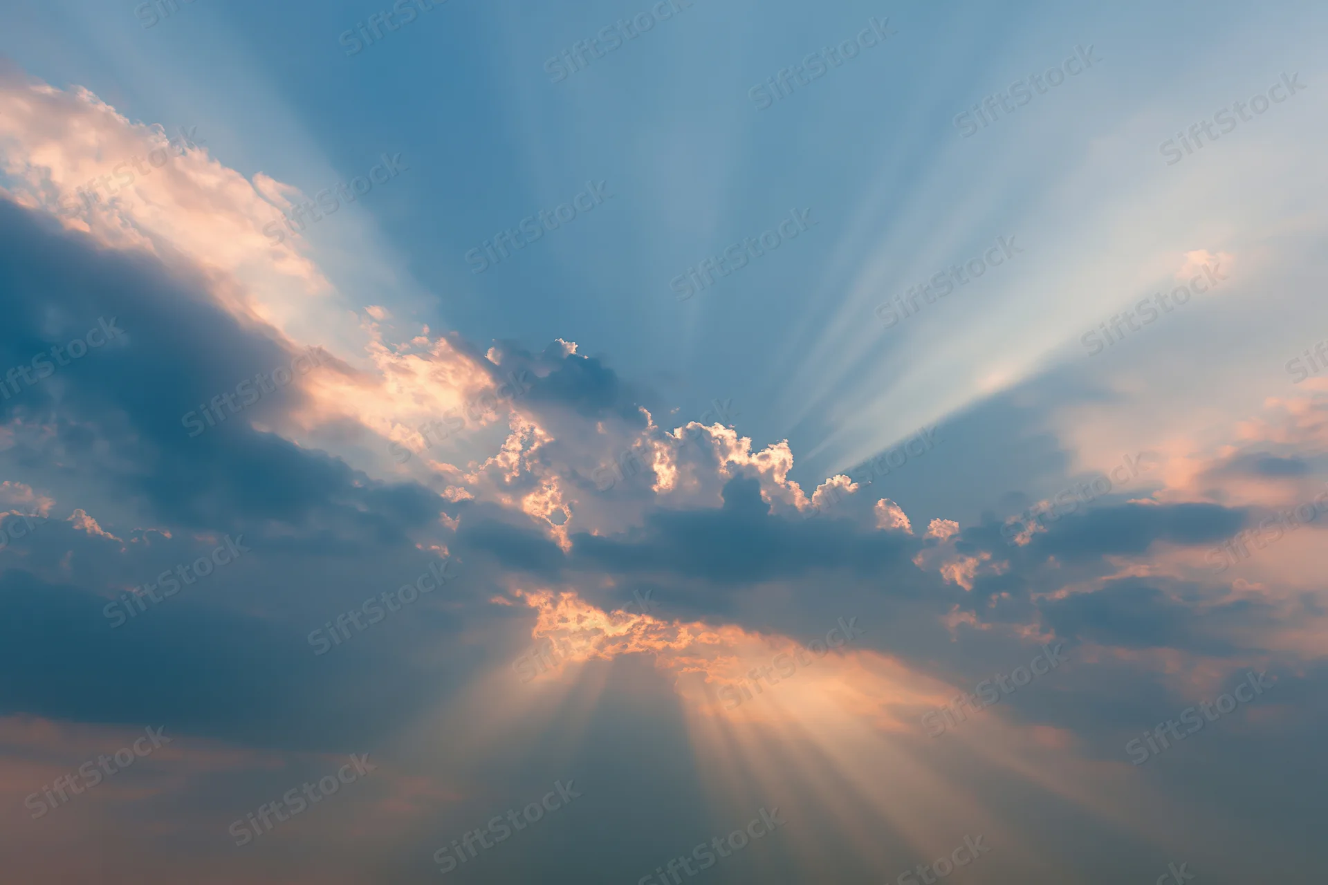 Sun rays breaking through layered clouds in an open sky