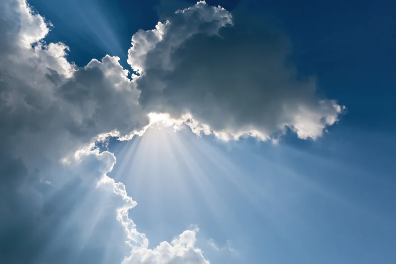 Sunlight breaking through dense clouds in a blue sky