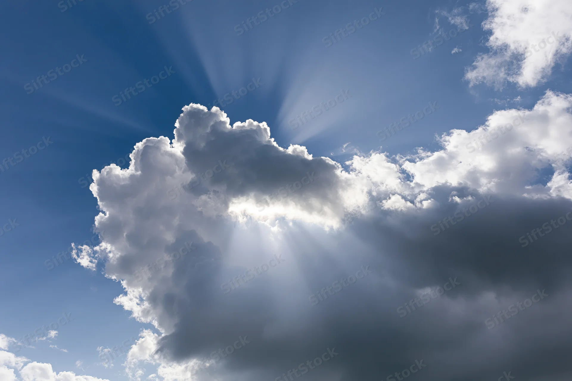 Sunlight breaking through dense clouds in a blue sky
