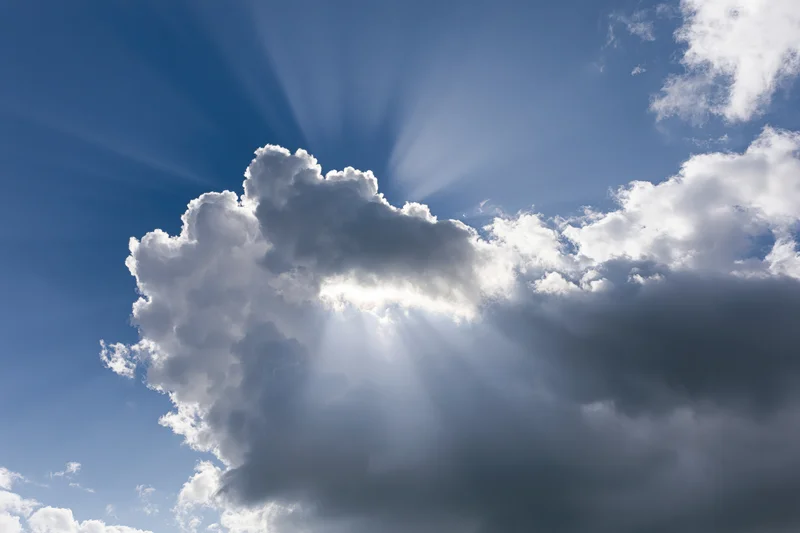 Sunlight breaking through dense clouds in a blue sky