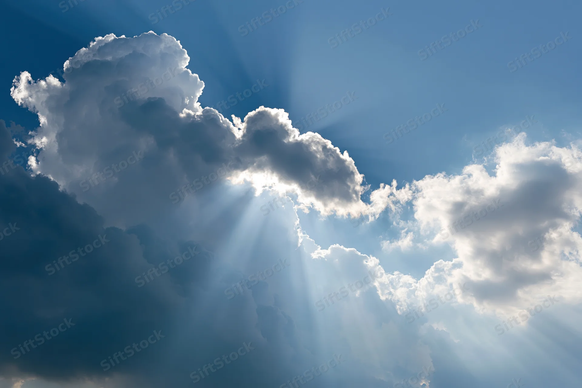 Sunlight breaking through dense clouds in a blue sky