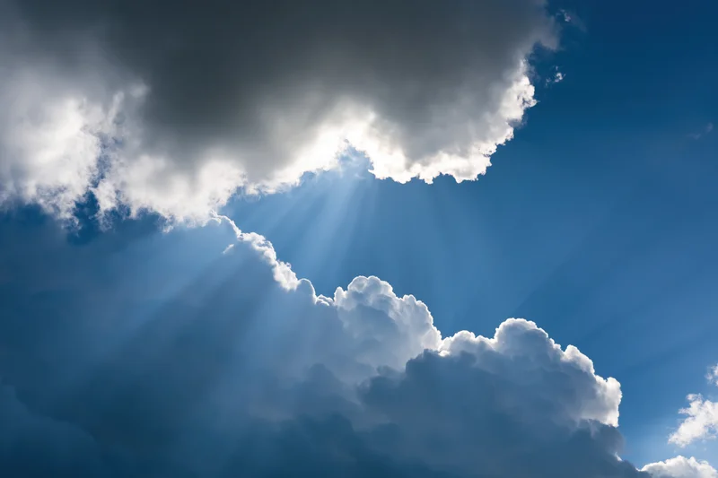 Sunlight breaking through dense clouds in a blue sky
