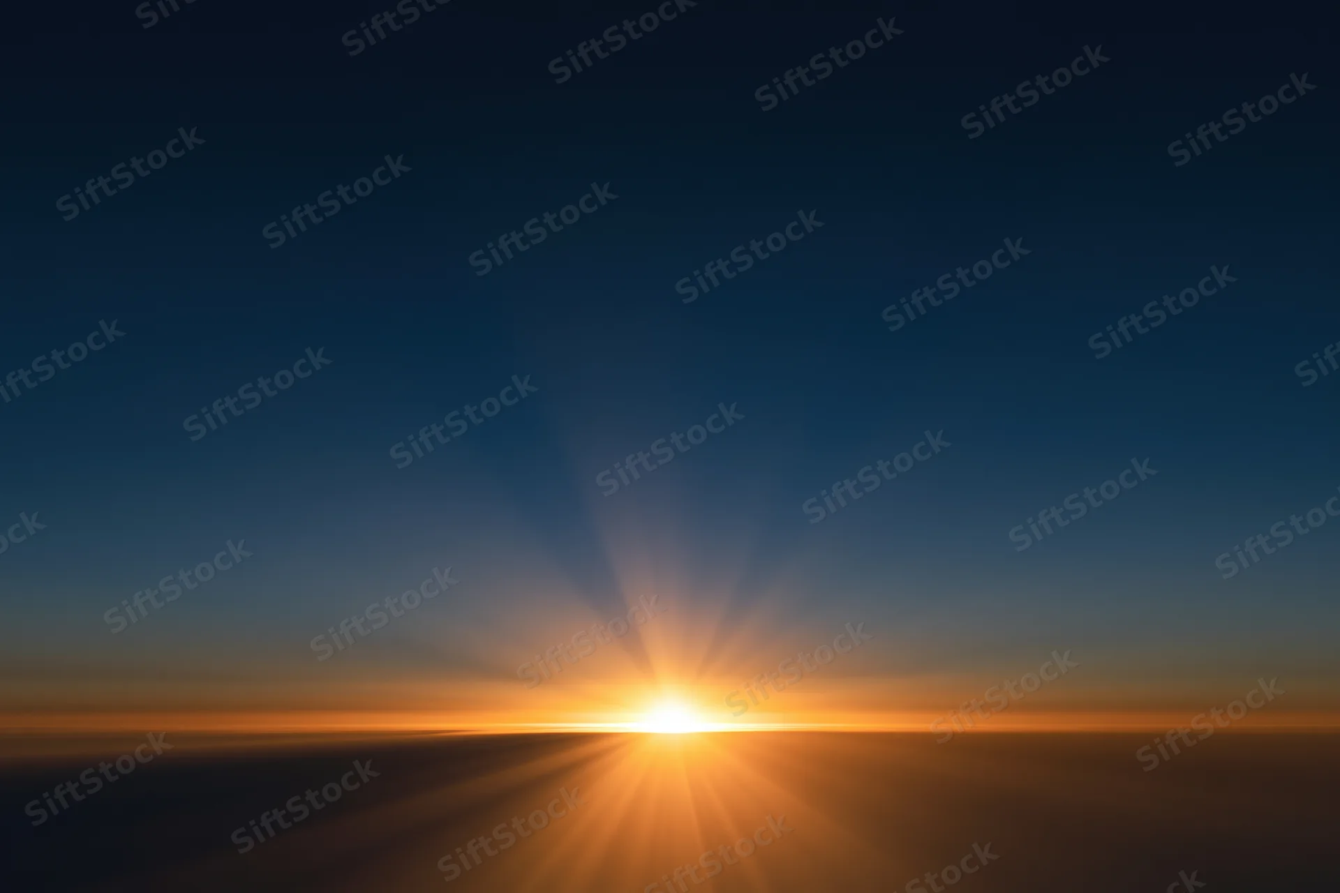 Sunrise radiating golden rays from the horizon above clouds during dawn