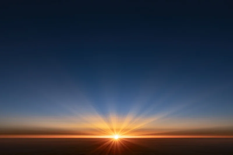 Sunrise radiating golden rays from the horizon across the sky