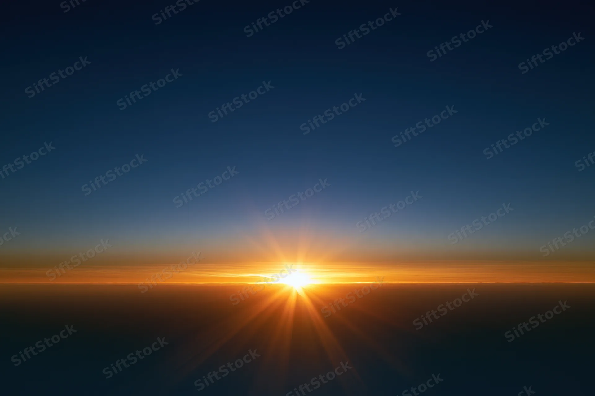 Sunrise light burst at horizon radiating golden rays upward across sky