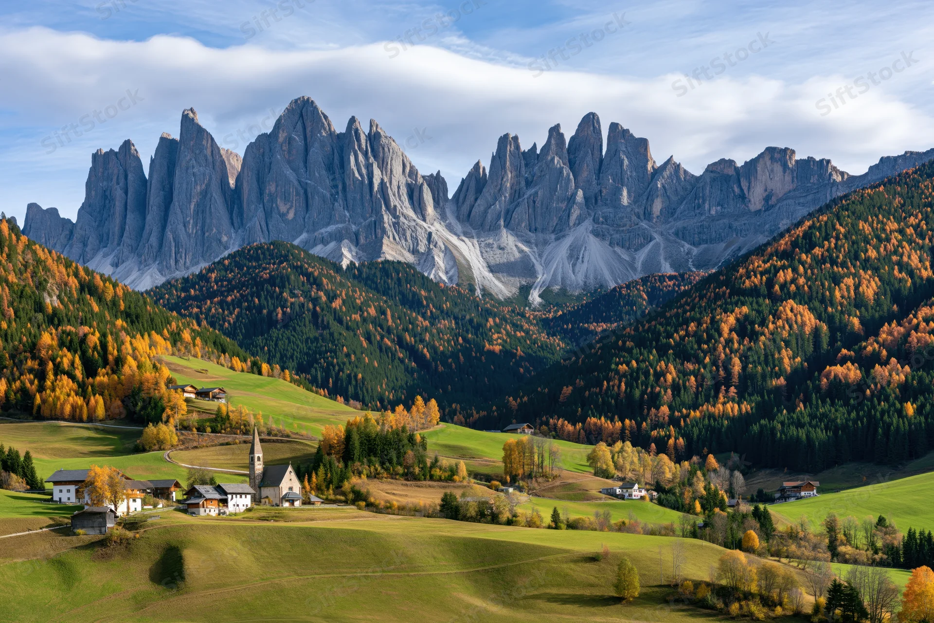 Alpine village nestled in a green valley with autumn foliage and towering dolomite mountains in the background