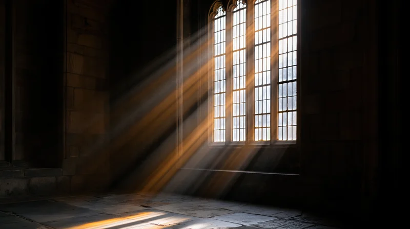 Volumetric light rays streaming through tall leaded cathedral window onto stone floor