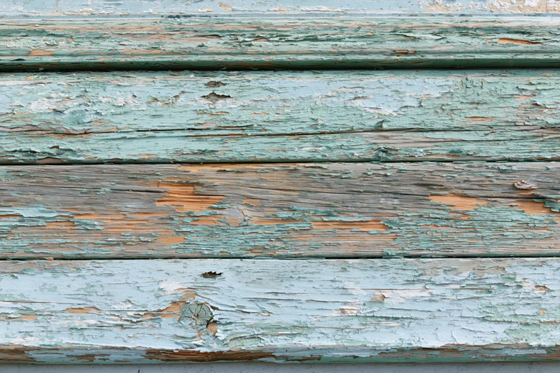 Horizontal weathered wooden planks with peeling green paint showing exposed wood grain