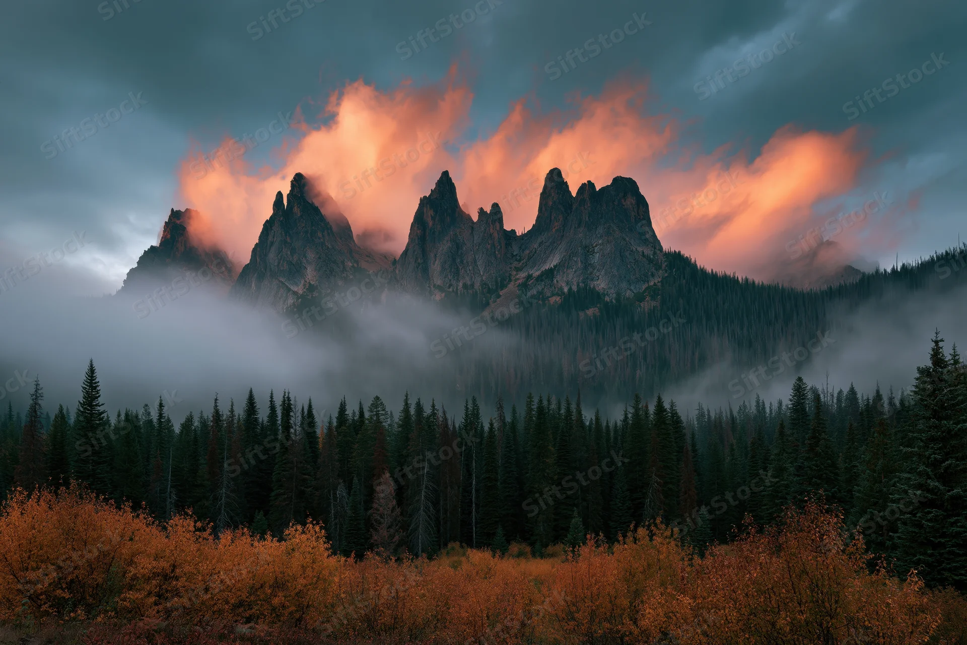 Jagged mountain peaks rising above foggy forest with autumn foliage in foreground