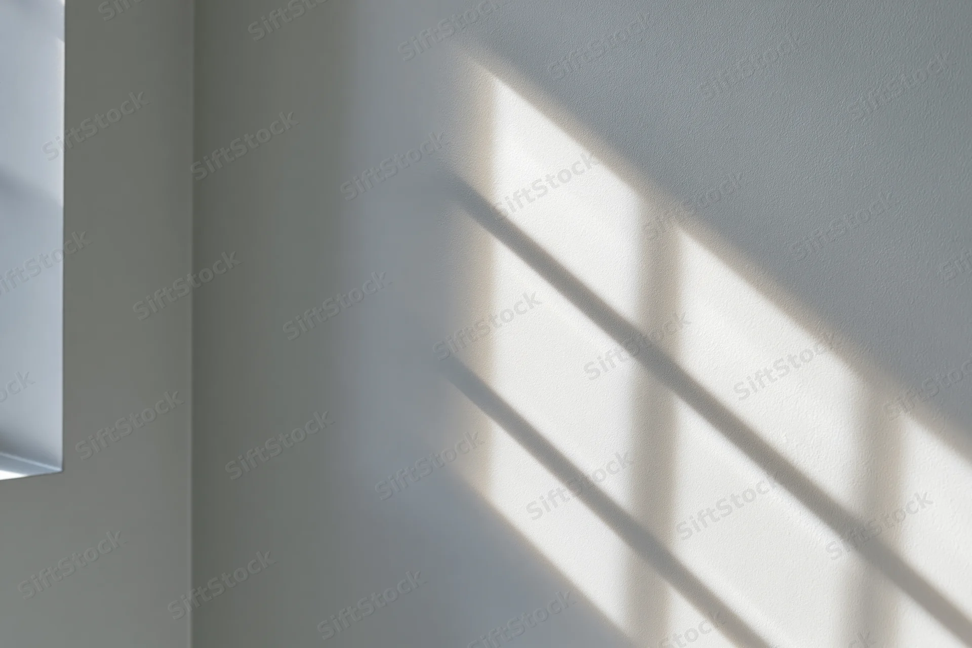 Diagonal window grid shadow cast across white-grey interior wall