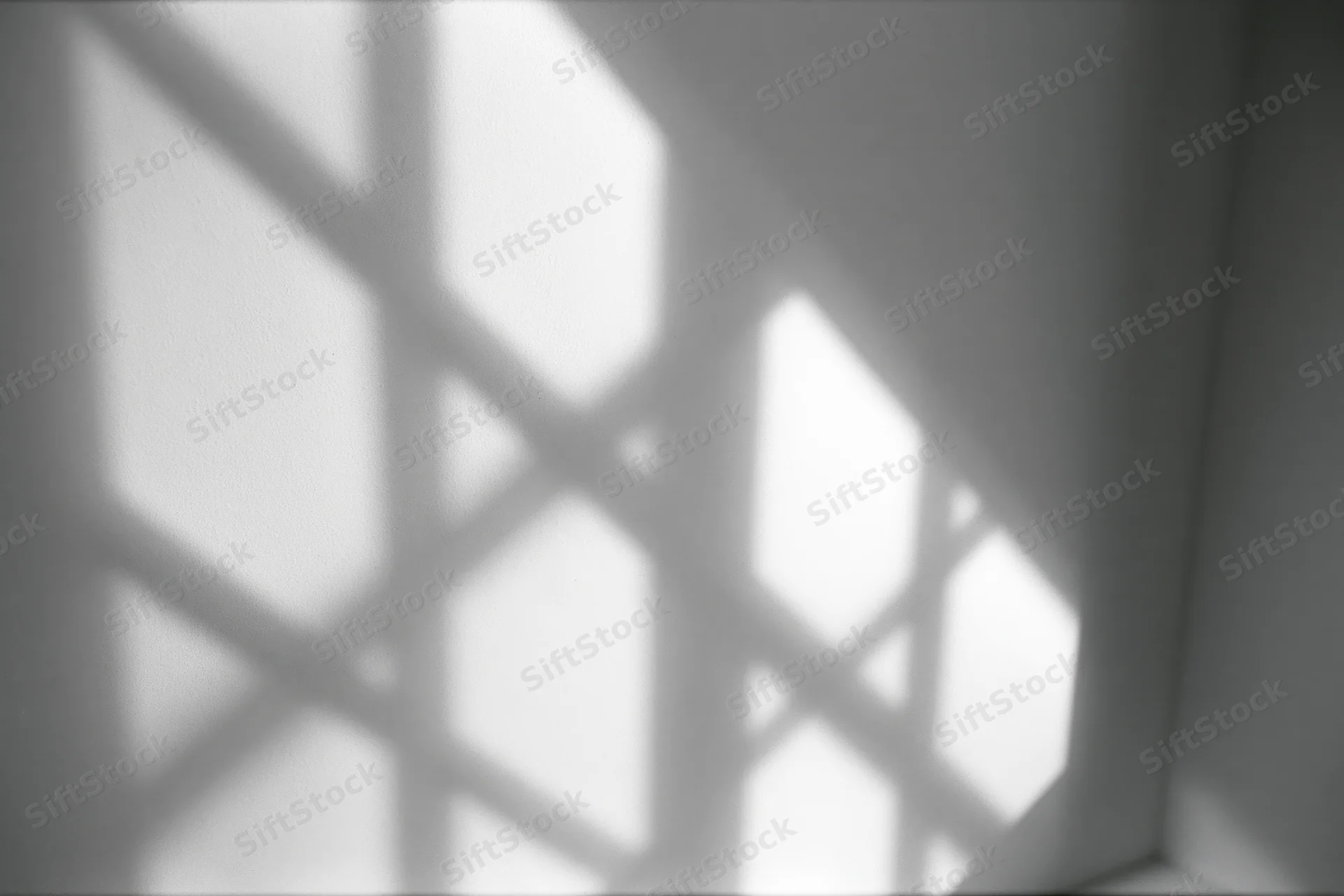 Diagonal shadow of window grid cast across plain white-grey wall in interior corner