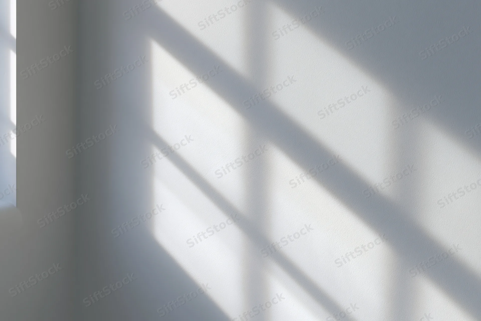 Diagonal window grid shadow cast across white wall in interior corner