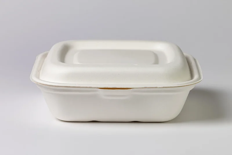 Closed white molded pulp clamshell food container sitting on plain white surface