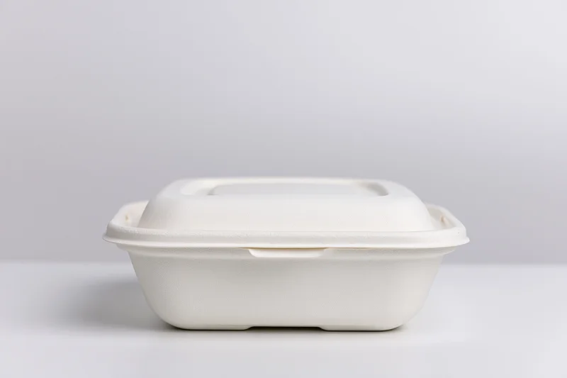 Closed white molded pulp clamshell food container on a plain white surface