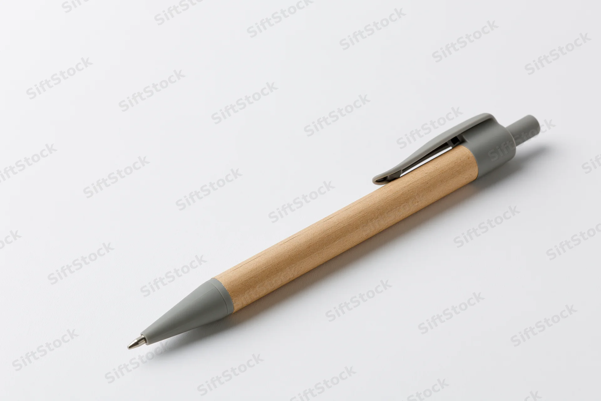 A recycled kraft paper ballpoint pen with grey plastic clip and wooden barrel lying on a white surface