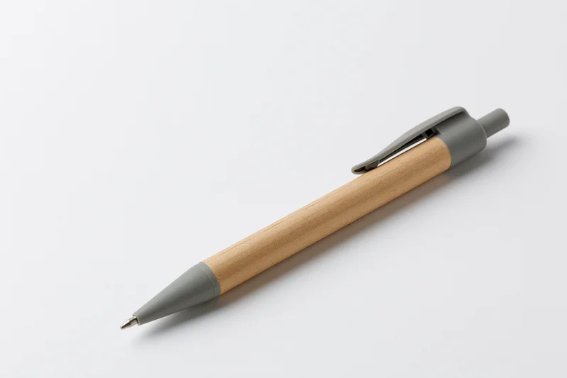 A recycled kraft paper ballpoint pen with grey plastic clip and wooden barrel lying on a white surface