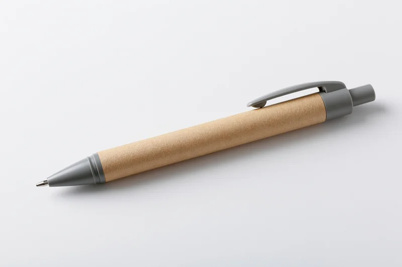 Recycled kraft paper ballpoint pen with grey plastic clip lying on white surface