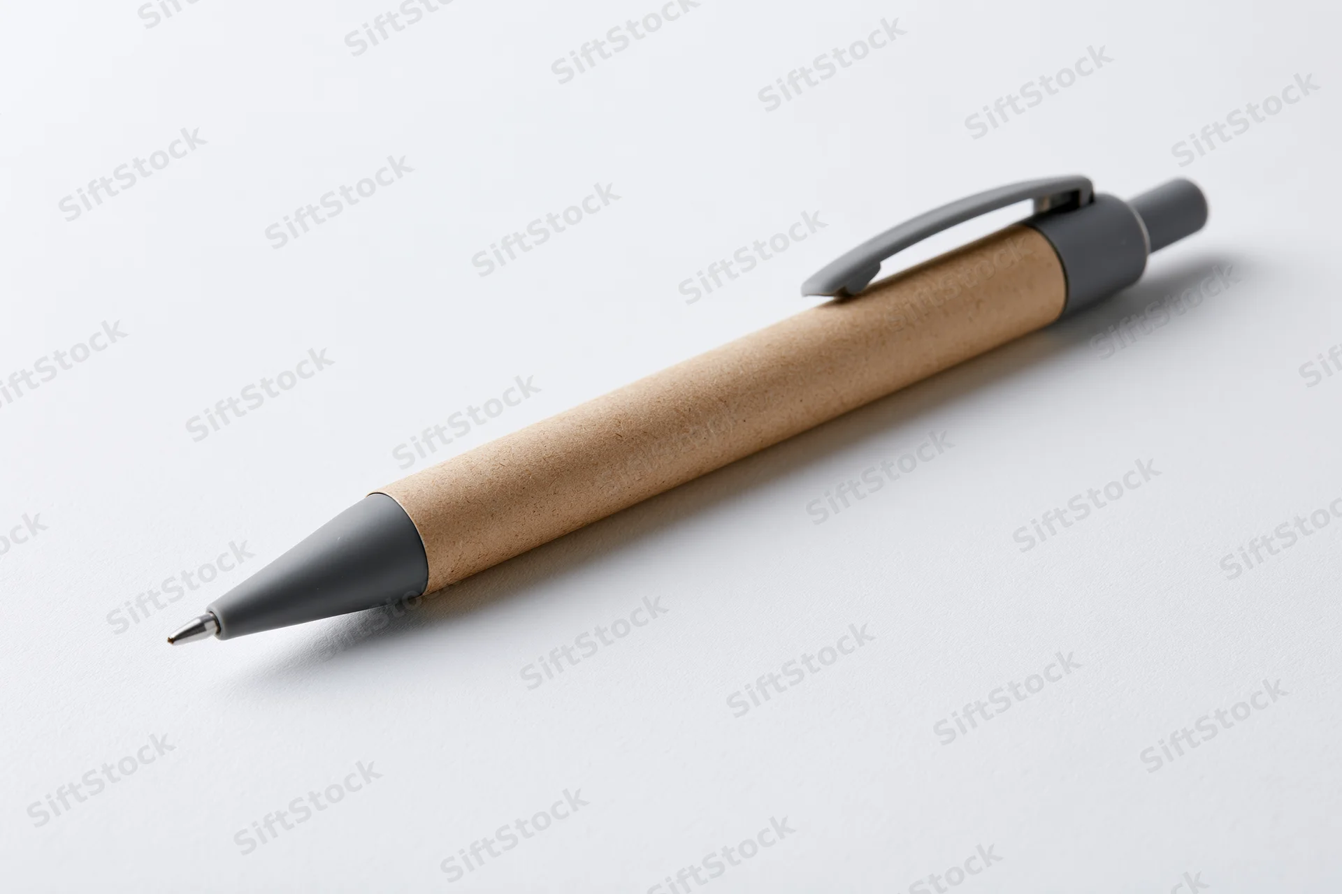 Recycled kraft paper ballpoint pen with grey plastic clip lying on white surface