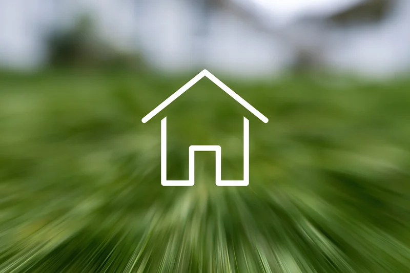 White house outline icon over blurred green grass field with copyspace