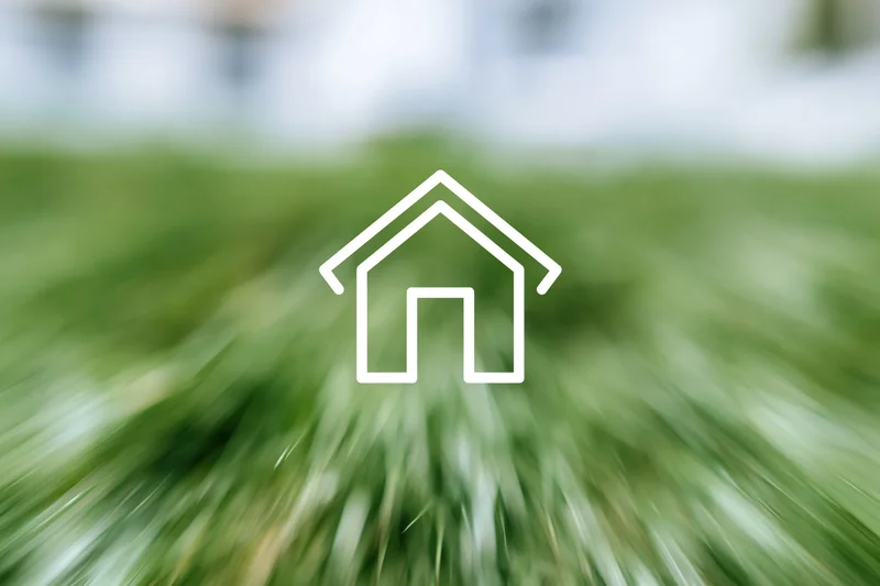 White outline house icon over blurred green grass background